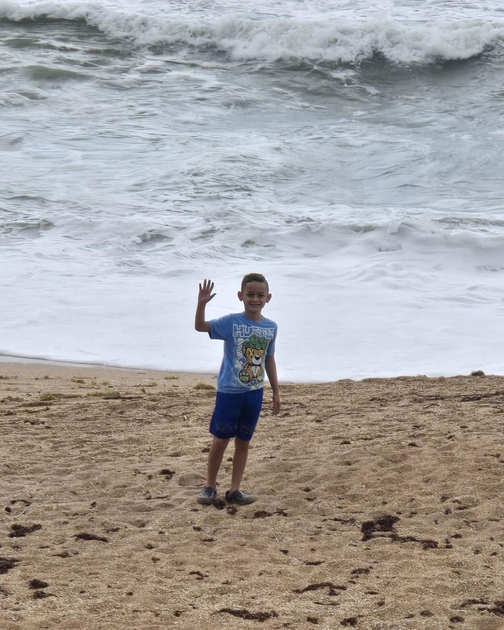 A child supported by the Lone Warrior Foundation waving on the beach